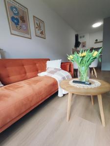 a living room with a couch and a table with flowers at Apartament MiA in Mrągowo