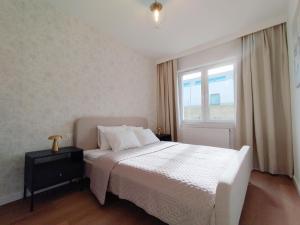 a bedroom with a white bed and a window at Apartament MiA in Mrągowo +16 photos