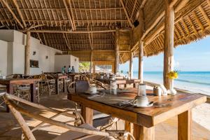 a restaurant on the beach with tables and chairs at NDAME Paje Hotel in Paje