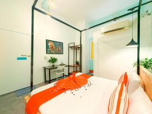 a bedroom with a white bed with an orange blanket at Social Backpacker Hostel & Rooftop Bar in Battambang