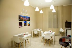 une salle à manger avec des tables et des chaises blanches dans l'établissement Svevo, à Cosenza