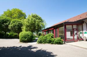 a red building with bushes in front of it at Sonnenblumenhof - Zimmer & Apartments in Mühlheim