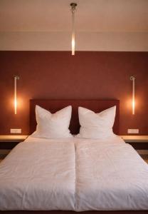a bed with white sheets and pillows in a room at Rex Palast in Memmingen
