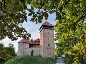 a castle on top of a hill with trees at Apartman Mali Muk 2, self check in in Karlovac