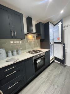 a kitchen with black cabinets and a stove at Stylish Central Kettering Apartment by SJP in Kettering