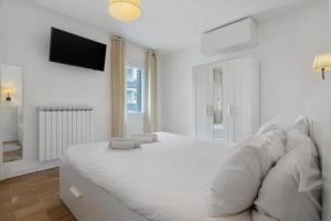 a white bedroom with a large white bed and a television at Venezia, 15 minutes from Venice, Parking,Shuttle airport, Train station Miranese in Mestre