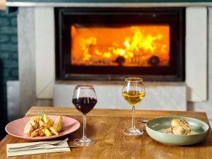 two glasses of wine and food on a table with a fireplace at Novotel Paris Pont De Sevres in Sèvres
