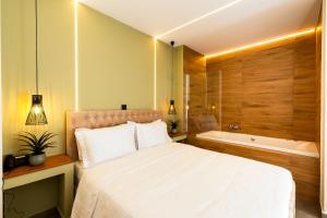 a bedroom with a large bed and a bath tub at Aether Athens Urban Hotel in Athens