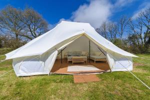 a white tent with a couch in a field at Boscoppa Farm-Emperor Tent 1 in St Austell