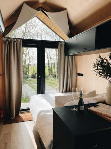 a bedroom with a bed and a table with wine glasses at Tiny Cabin met airco en privé hottub in Rutten
