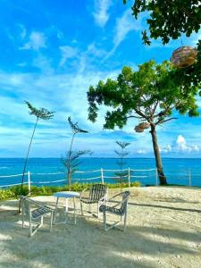 a table and chairs on a beach with the ocean at Seaside Living Studio Unit in Maribago