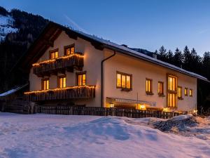 a house in the snow with lights on it at Gasthof Barlida in Lainach