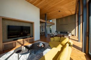 a living room with a yellow couch and a large tv at Zai-On 在恩 in Kutchan