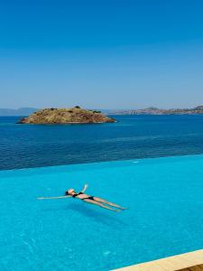 a person in the water with an island in the background at Birds Bay Resort in Petra +17 photos