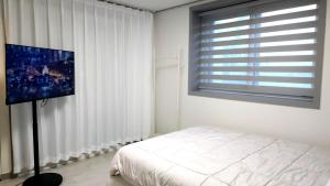 a bedroom with a bed and a flat screen tv at Pine-tree stay Mini in Samgong