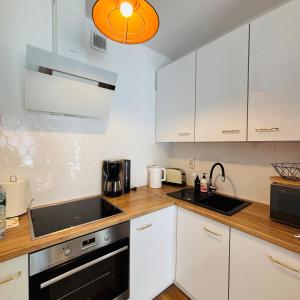 a kitchen with white cabinets and a sink at Lotus Apartments Natura parking balcony in Ostrołęka