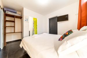 a bedroom with a large white bed and a shelf at La Mezina in Saint-Joseph