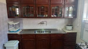 a kitchen with wooden cabinets and a sink at staylikehome guesthouse in Nieuw Nickerie +145 photos