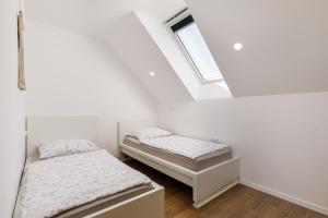 two beds in a white room with a window at Vila Šenčur in Šenčur