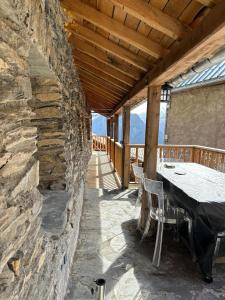 a table and chairs on a porch with a stone wall at Les Racines Chalet in Villard-Reculas