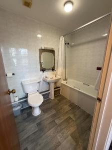 a bathroom with a toilet and a sink and a tub at The Grand Hotel in Port Talbot +54 photos