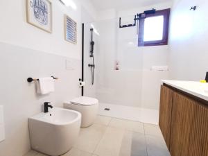a white bathroom with a toilet and a sink at Domus Luna in Teulada