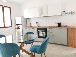 a kitchen with a glass table and blue chairs at Domus Luna in Teulada