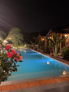 a swimming pool at night with red flowers at Flora Garden Homestay in Xuân Sơn