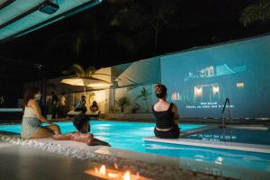 a group of people sitting around a swimming pool at White Tiger Villa in Goa