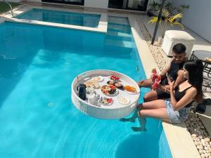 a man and woman sitting next to a table in a swimming pool at White Tiger Villa in Goa