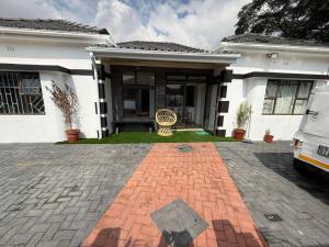 a white house with a brick driveway at Black & White Guest House in Parow