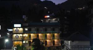 a large building with lights on it at night at Young Monk Hostel Bhagsu,Mcleodganj in Dharamshala +3 photos