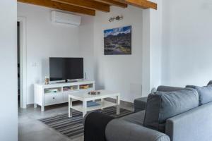 a living room with a couch and a tv at CASA IBON 1A pool view Playa Roca in Costa Teguise