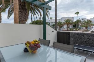 a bowl of fruit on a glass table on a balcony at CASA IBON 1A pool view Playa Roca in Costa Teguise