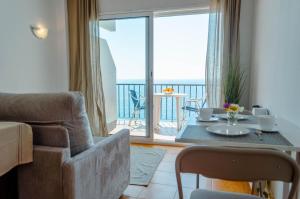 a living room with a couch and a table and a balcony at Apartamentos Cala Llevado in Tossa de Mar