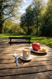 a cup of coffee and a apple on a wooden table at Chez Elise et Joseph in Mons-Boubert