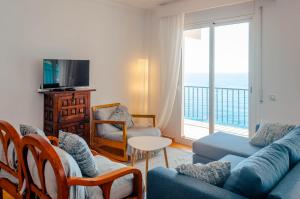 a living room with a couch and chairs and a balcony at Apartamentos Cala Llevado in Tossa de Mar