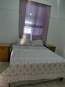 a bed in a bedroom with a purple window at Ocean River in Gqeberha