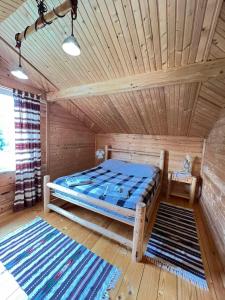 a bed in a wooden room with rugs at Gesteruv in Sheshory