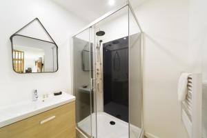 a glass shower in a bathroom with a sink and a mirror at Les cabanes du Lac in Sévignac-Thèze