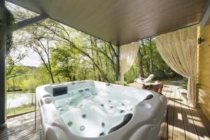 a jacuzzi tub on a deck with a view at Les cabanes du Lac in Sévignac-Thèze
