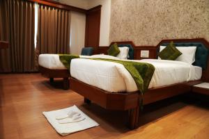 two beds in a hotel room with a scale on the floor at The Indies 365 Hotel in Bangalore +19 photos