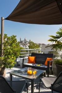 a patio with a couch and tables on a balcony at Citadines Montmartre Paris in Paris