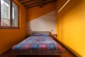 a bed in a room with yellow walls and a window at Il NIDO-Attico Siena Centro con vista Duomo e Torre Del Mangia in Siena
