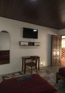 a bedroom with a table and a television on the wall at Umang-umang Chalet in Kampong Tanjong Dahan