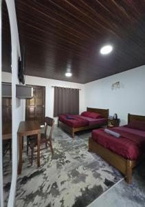 a room with two beds and a desk and a table at Umang-umang Chalet in Kampong Tanjong Dahan