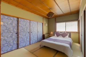 a bedroom with a large bed with purple pillows at Chikyuutabikazoku USJ Ⅱ in Osaka +60 photos