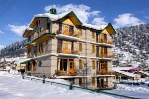 a large wooden building in the snow with snow at Mountain Route Cottage in Manāli