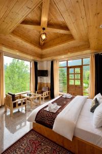 a bedroom with a large bed in a room with windows at Mountain Route Cottage in Manāli