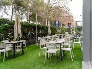 a row of tables and chairs with umbrellas on grass at Ibis Barcelona Mollet in Mollet del Vallès